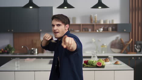 portrait of cheerful man enjoying dance on kitchen. sexy man smiling to camera