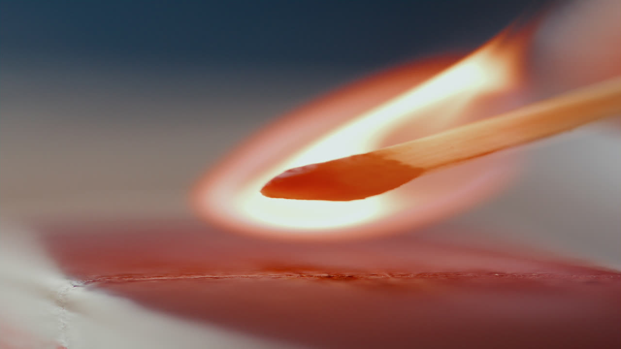Gros plan sur une allumette frottée sur une boîte, créant une flamme.