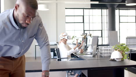 using vr headset, woman working at desk in modern office with colleague nearby