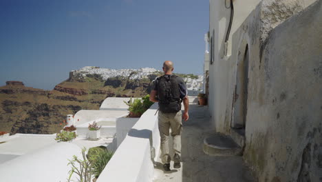 siguiendo a un hombre caminando en la isla de santorini en un día soleado