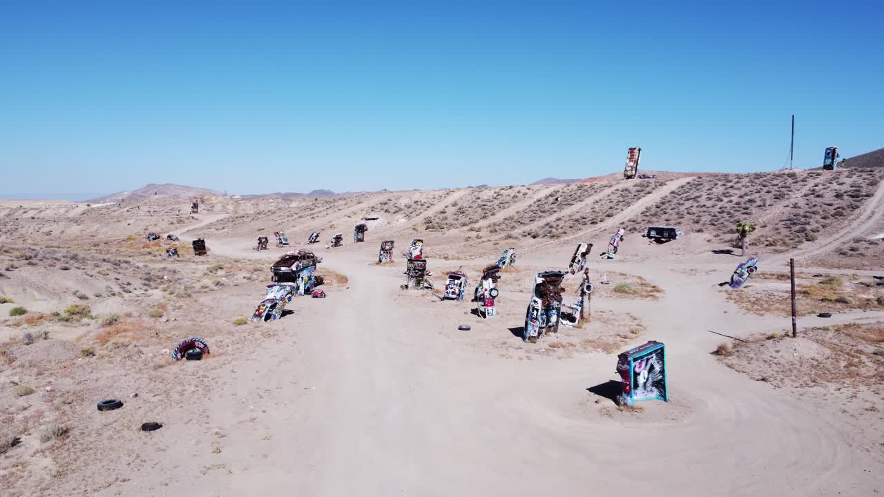 A drone flying over a car graveyard in a desert.