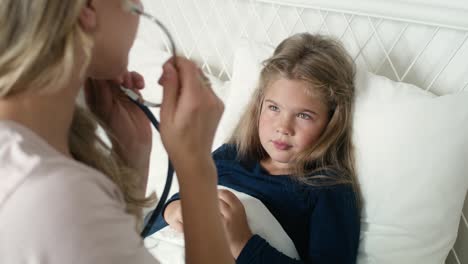 pediatra examinando los pulmones de una niña enferma en la cama