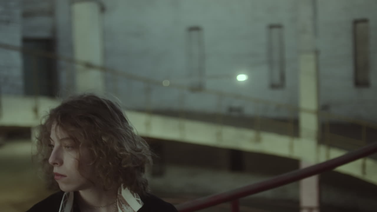 Pensive young woman in a dimly lit industrial setting