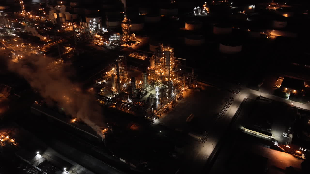 gran planta de refinería de petróleo con humo espeso proveniente de las chimeneas, vista aérea nocturna