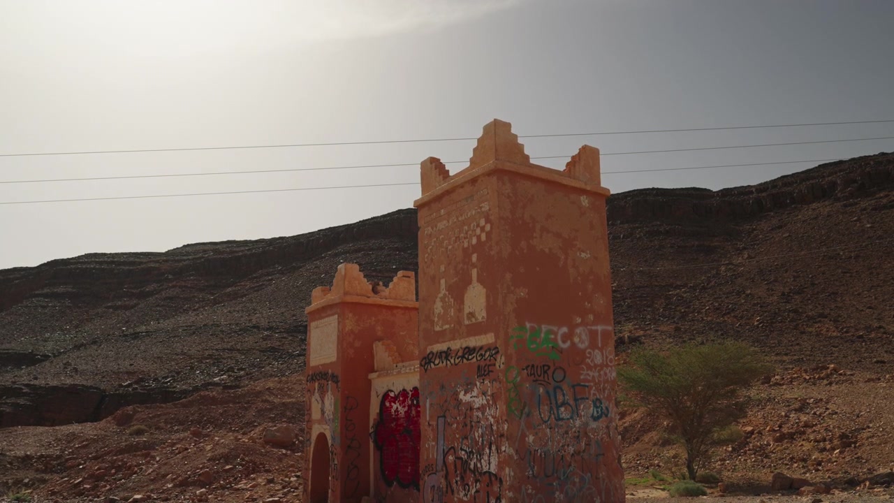 Vecchie torri dipinte con graffiti che si ergono accanto a una montagna rocciosa nel deserto in Marocco