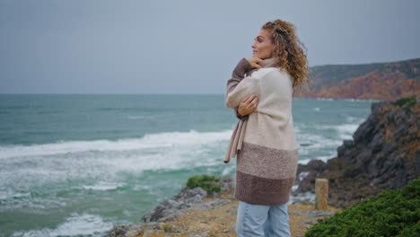 carefree tourist standing sea shore looking on gray horizon at windy vacation.