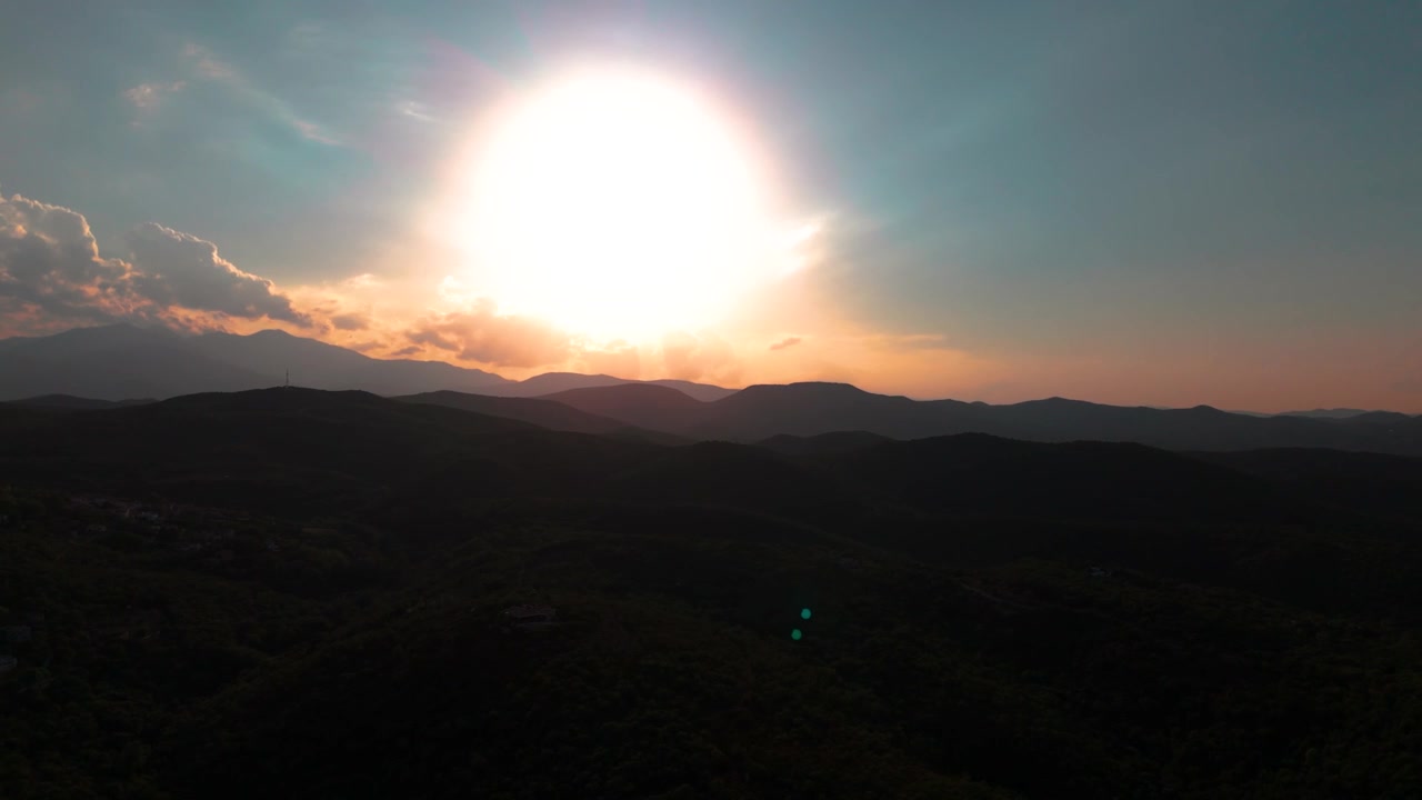 Aerial view glides across dark mountains beneath a bright solar eclipse