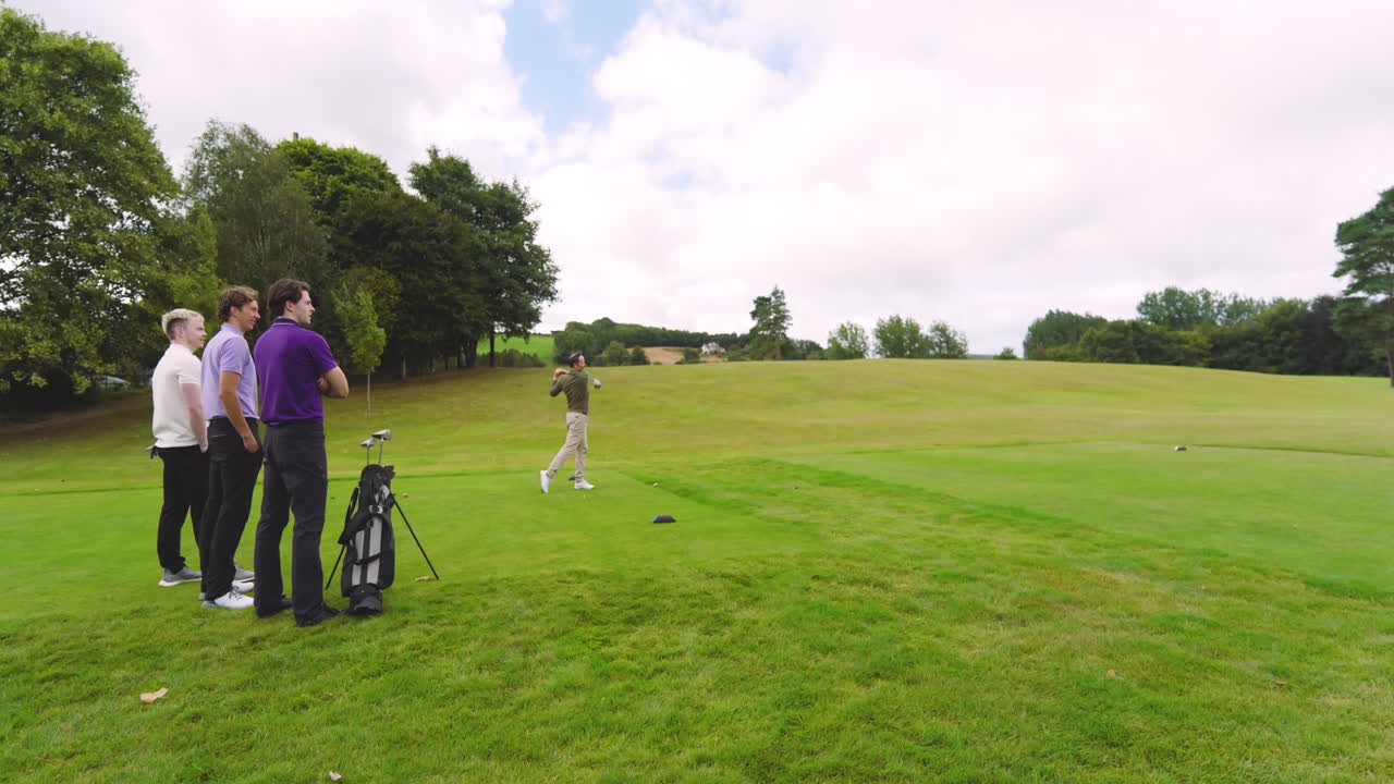 Male golf players playing golf, one player knocks golf ball out on golf course, copy space