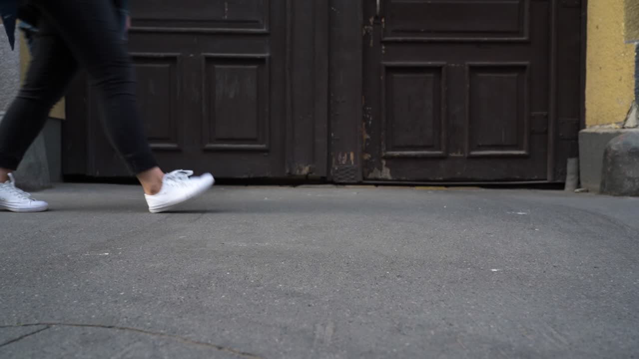 primer plano de una persona caminando por una calle pavimentada con zapatillas blancas