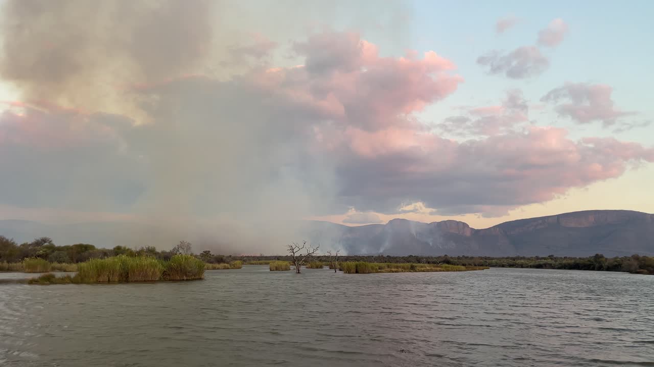 A mesmerizing view of a glowing fire on the African shoreline, captured from a boat during a serene safari evening.