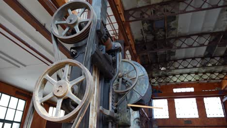 panning shot of a geared machine from an old forge inside a workshop