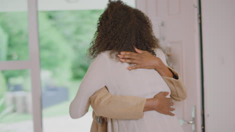 adult daughter greeting senior mother as she arrives to celebrate christmas at home