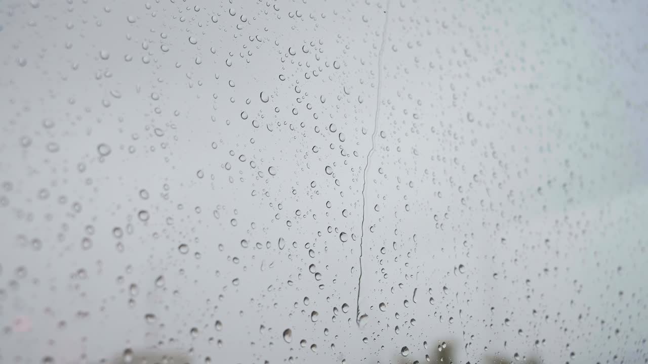 Un filmato al rallentatore di un primo piano di gocce di pioggia intense visto attraverso un vetro di finestra