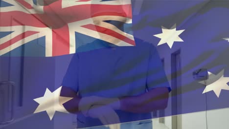 Die-Australische-Flagge-Weht-über-Einem-Kaukasischen-älteren-Männlichen-Gesundheitshelfer,-Der-Im-Krankenhaus-OP-Handschuhe-Trägt