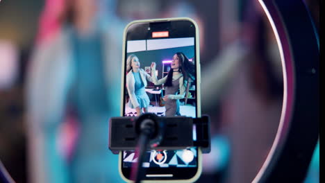 women recording a vlog on a smartphone using a ring light
