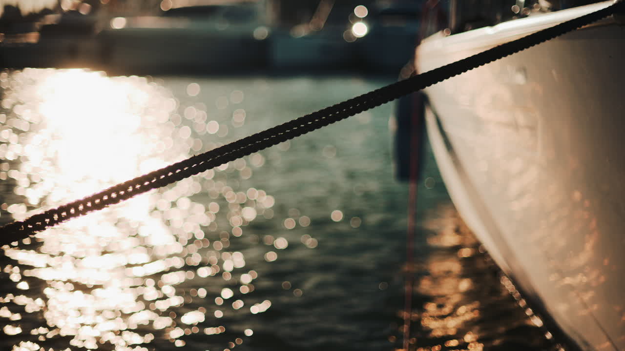 Golden sunlight shimmering on the side of a yacht floating on calm water