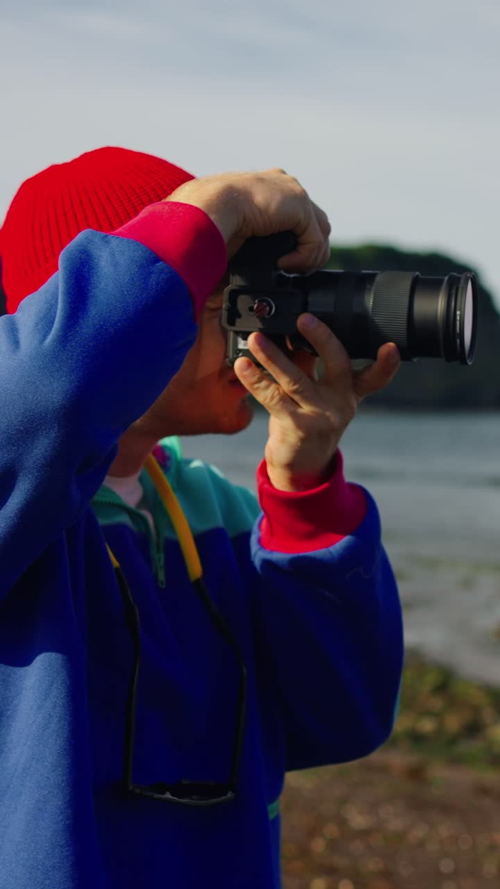 Giovane uomo che scatta foto con una macchina fotografica sulla costa
