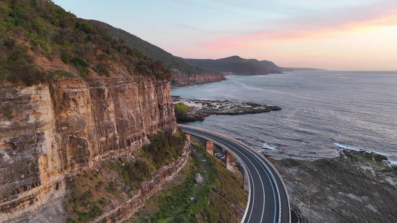 Cinematic aerial view of the Sea Cliff Bridge, highlighting its stunning architecture and the rugged cliffs of New South Wales.