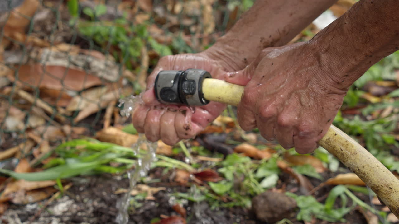 Man Using A Hose To Wash Hands During Planting - Close Up