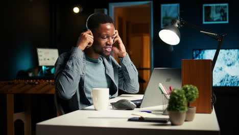 african american man video conferencing with his work colleagues at home office