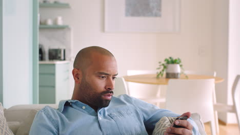 Man-on-living-room-sofa-using-phone-on-social