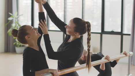 female teacher corrects the arm position of the gymnastic girl in ballet class