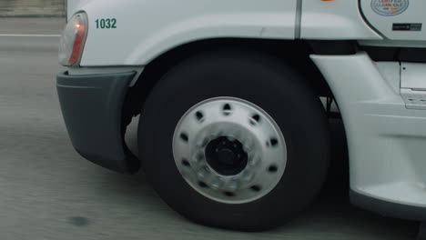 close up of modern semi-truck front wheel rolling on freeway