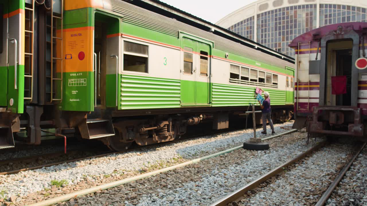 Un treno passeggeri verde si trova sui binari di una stazione storica in una giornata di sole