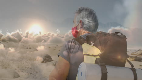 caucasian senior man in face mask hiking on the coast, over fast moving clouds