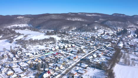 Ciudad-Encantadora-Al-Pie-De-Las-Montañas-Cubiertas-De-Nieve-Espesa-En-Invierno---Tiro-Aéreo