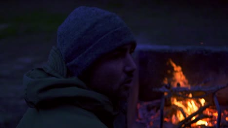 Man-in-a-hat-in-the-twilight-next-to-a-bonfire-with-fire