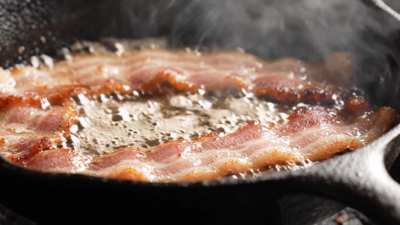 Pancetta sfrigolante che cuoce in una padella di ghisa: Un viaggio visivo appetitoso attraverso la perfezione croccante e l'arte della preparazione della pancetta.