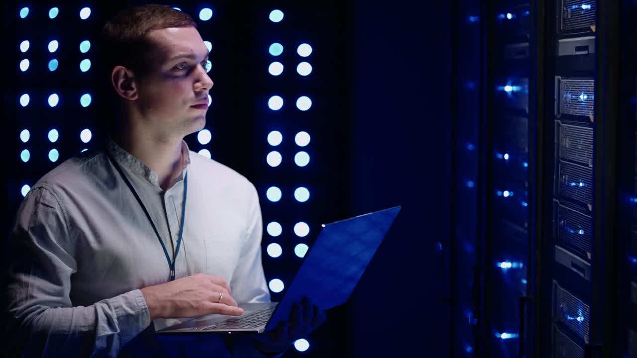 정보의 디지털화 개념: 그것은 노트북과 함께 서버 랙 앞에 서있는 전문가 그는 터치 제스처로 데이터 센터를 활성화합니다. 네트워크 데이터