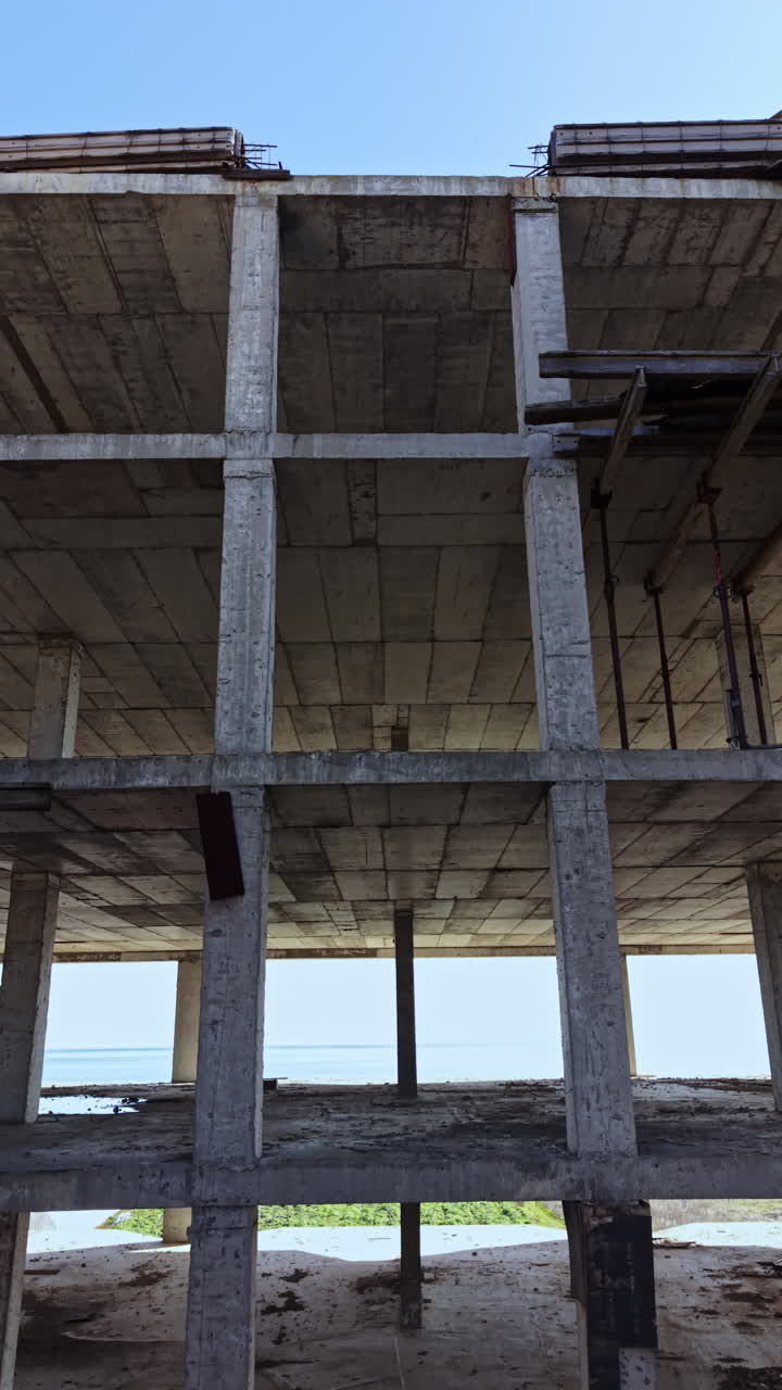 Exploring the skeletal remains of a half-finished building by the water on a sunny day evokes thoughts of past dreams and future possibilities in an urban landscape