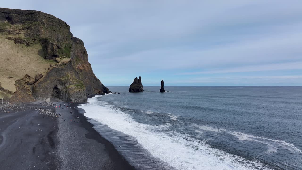 산의 장엄함, 해변의 평온함, 그리고 그것을 즐기는 사람들, 검은 모래 해변.
