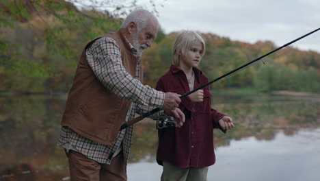 grandfather teaching grandson how to fish by an autumn lake