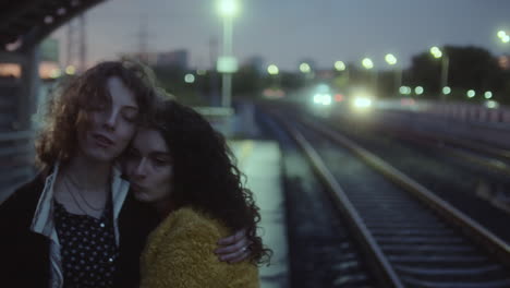 girlfriends embracing and talking at railway station