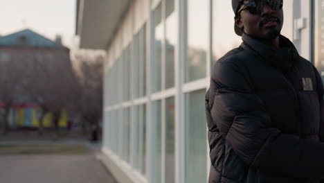 close up of hand pulling white glass door handle to exit modern building during winter evening, with soft reflection of jacket and outdoor scenery creating warm yet urban atmosphere