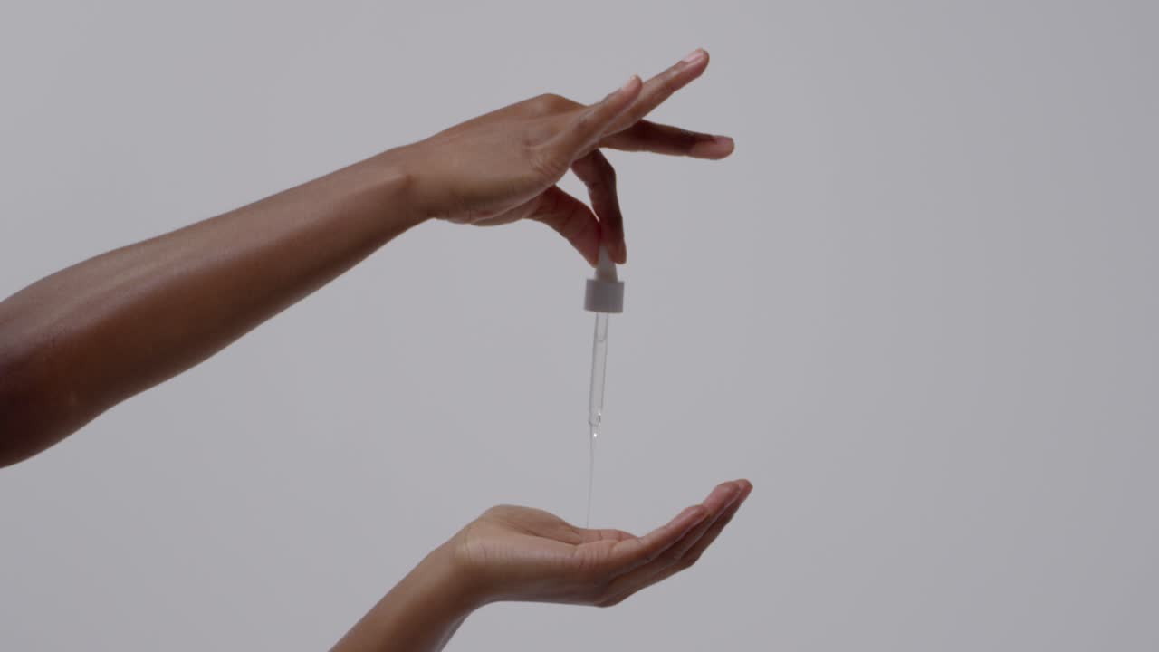 primer plano de una mujer apretando un gotero de producto de belleza en la mano sobre un fondo blanco 1