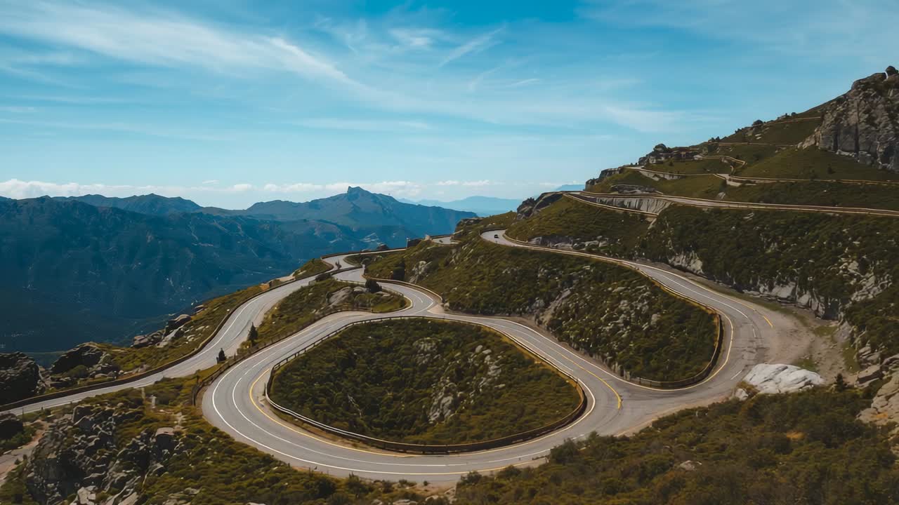 Initiating drone panning over winding mountain road at high-altitude pass, with yellow centerlines