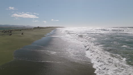 Aerial view of Smith River coastline in California, aerial dolly shot along the shore with waves crashing against the rocks