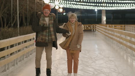 una pareja de mayores patinando sobre hielo por la noche.