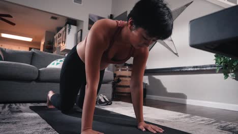 Joven-Mujer-Asiática-Haciendo-Estiramientos-De-Yoga-En-La-Sala-De-Estar-Mirando-Hacia-Abajo-El-Flujo-De-Vinyasa-De-Perro-Feliz-Durante-El-Entrenamiento-A-Cámara-Lenta