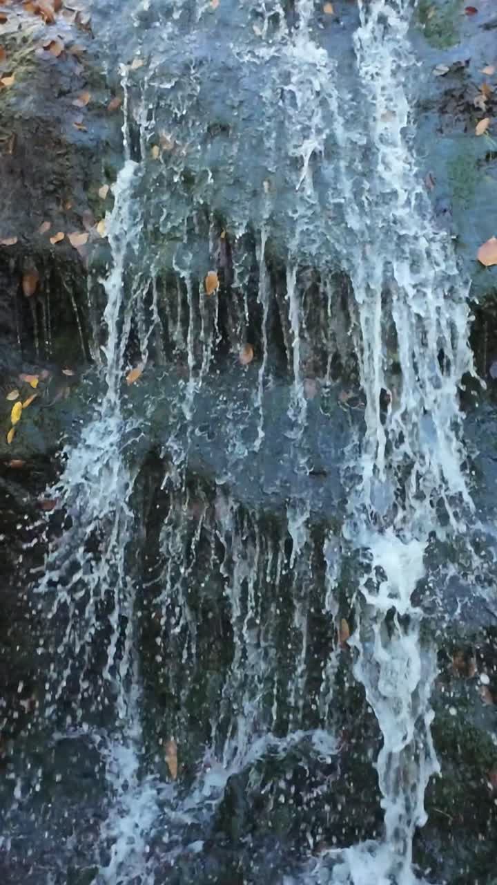 Schermo verticale. Le correnti furiose del torrente si infrangono contro pietre affilate nel caos. Un impetuoso ruscello di montagna si scontra violentemente con rocce invadenti tra la turbolenza e l'interruzione del flusso d'acqua.