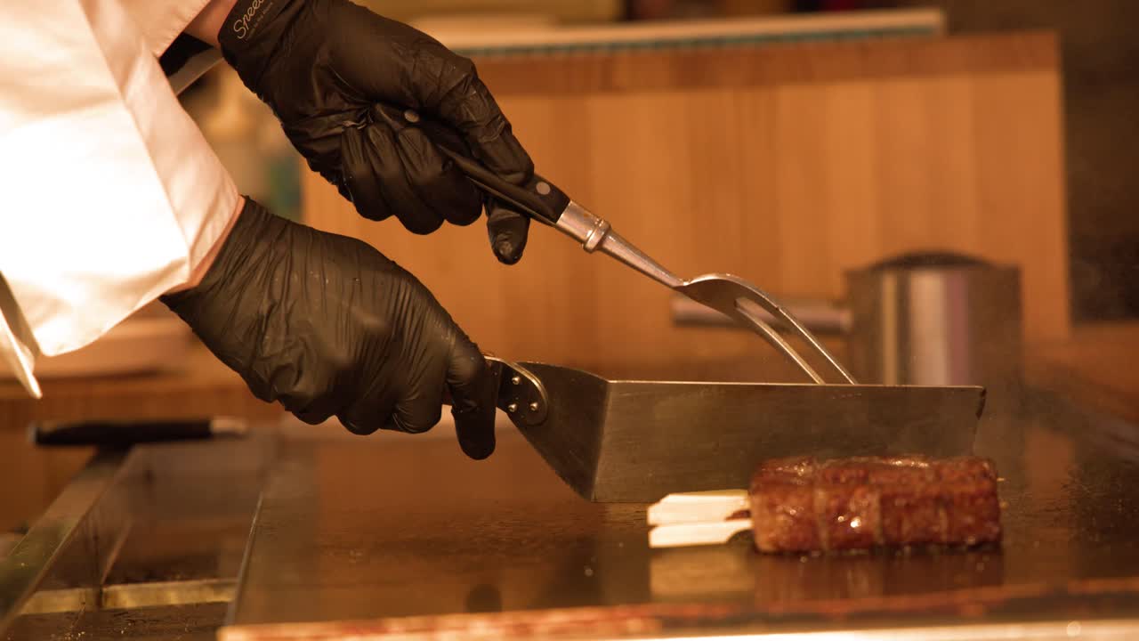 Uno chef professionista prepara abilmente manzo Wagyu gourmet su una piastra teppanyaki calda a Tokyo.