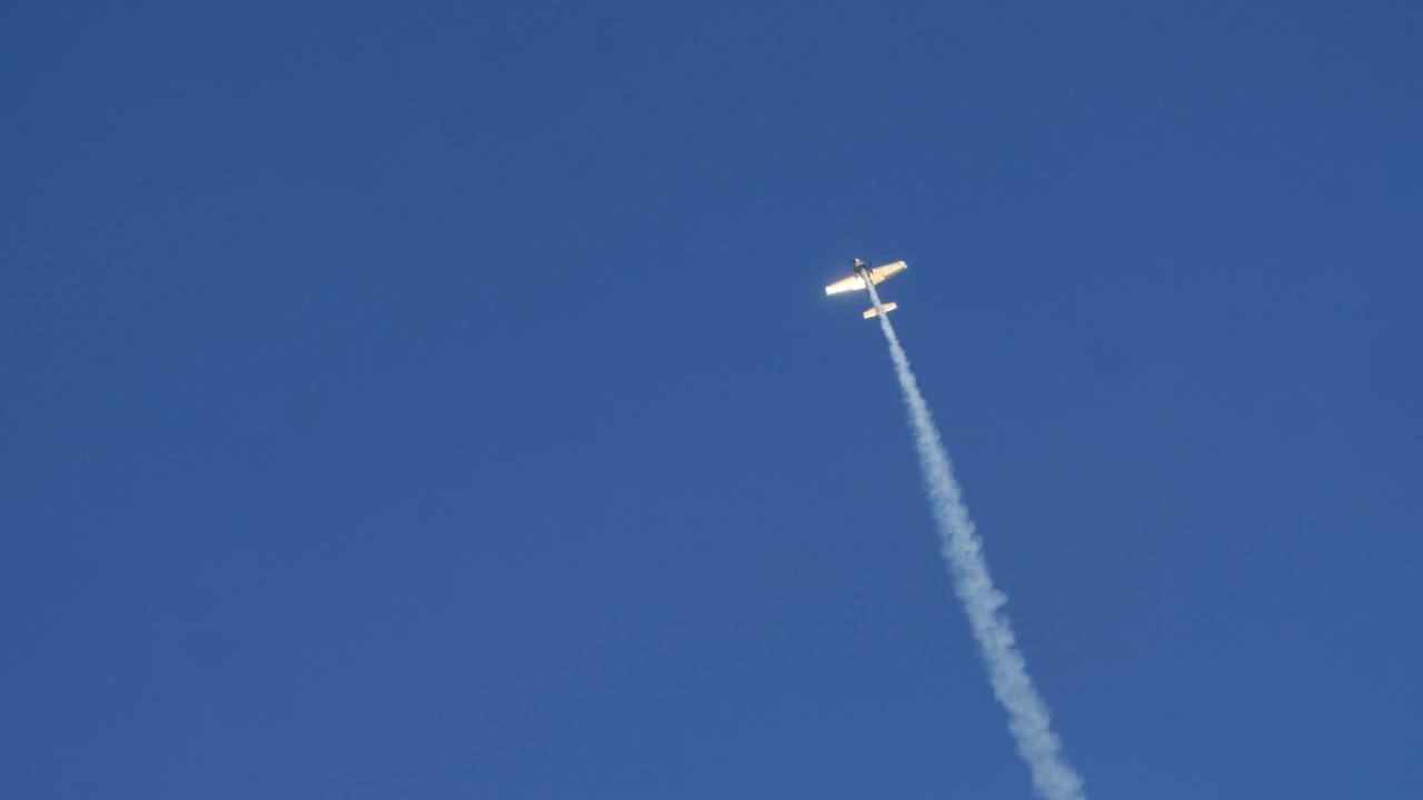 Airplane flying in a blue sky leaving a smoke trail