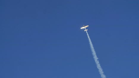 Airplane flying in a blue sky leaving a smoke trail