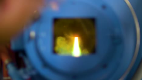 hombre mirando a través de la ventana del horno de arco de plasma fundiendo metal