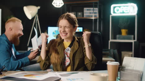 overjoyed colleagues congratulating each other at workplace