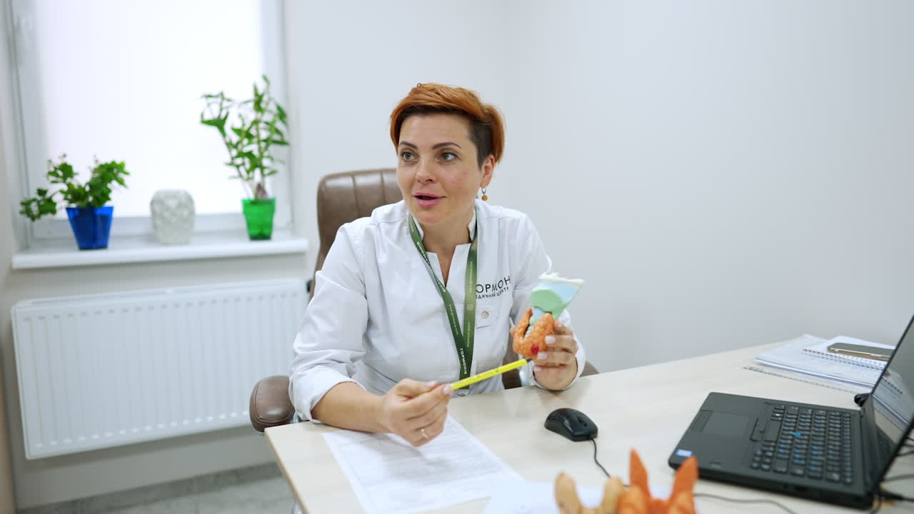 Kyiv, Ukraine, 2 August 2025: Doctor explains a medical problem using a model. Female physician in a white coat consults a patient at a desk in a bright office